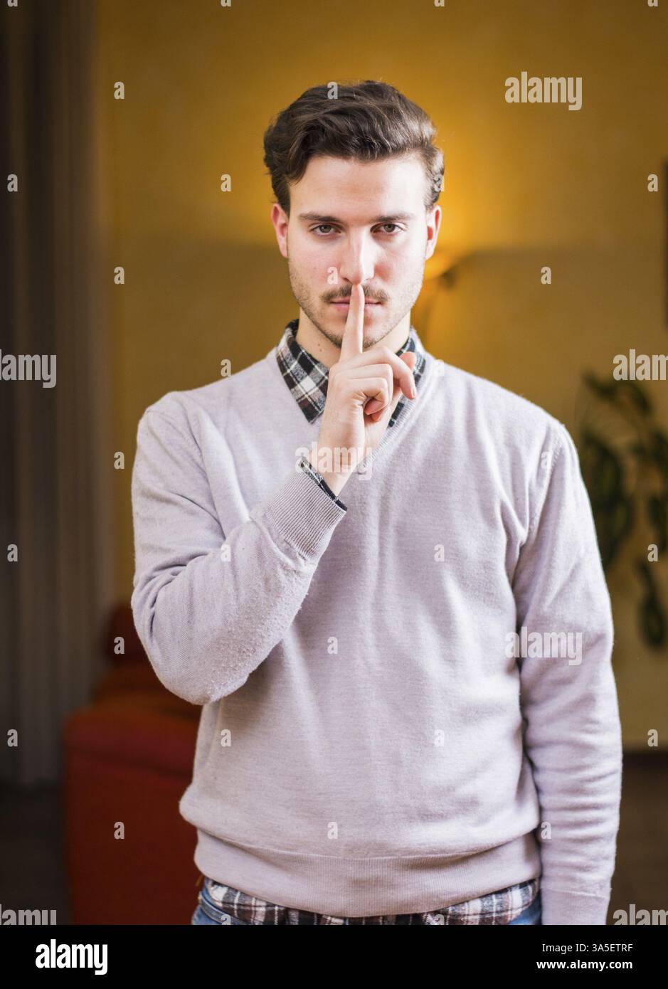 Hübscher junger Mann tun Hush Schild mit Finger auf Lippen, Blick in die Kamera. Vor Ort Stockfoto