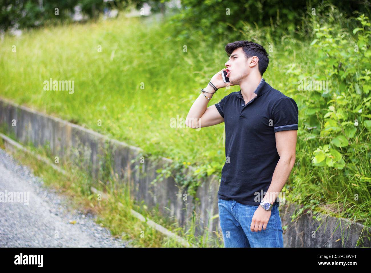 Schönen jungen Mann auf einer Straßenseite anrufen auf Handy und warten für Taxi Taxi Stockfoto