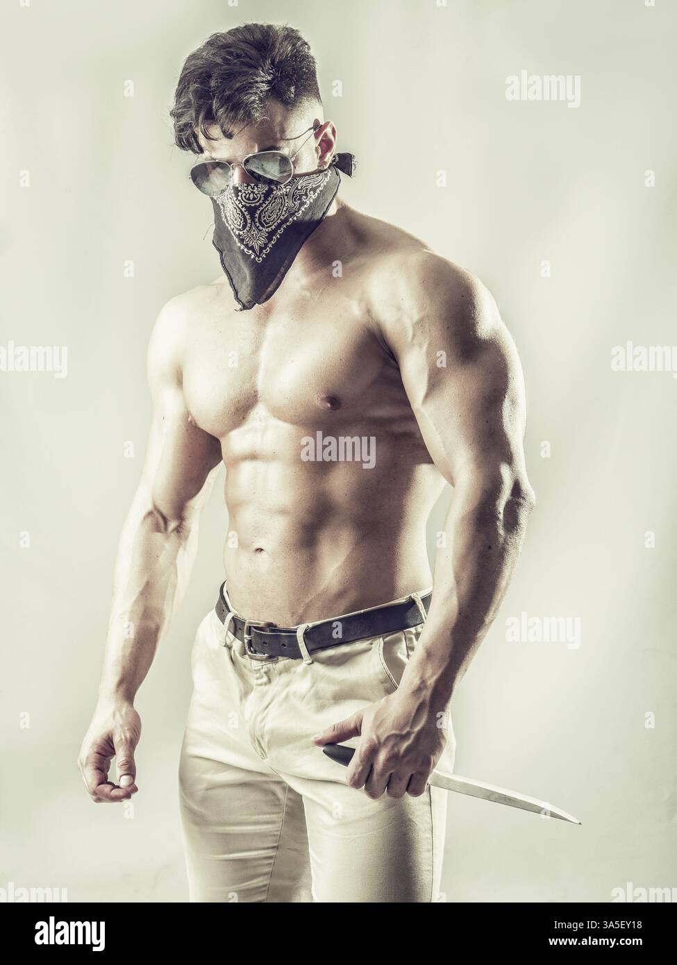 Schöner muskulöser junger Mann mit Maske über dem Gesicht als Räuber oder Räuber Stockfoto