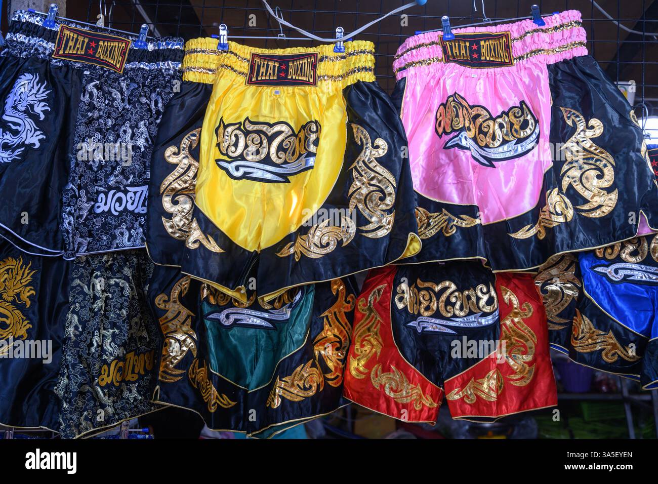 Mae Klong, Thailand. März 2025. Muay Thai Kampfkunst Boxshorts zum Verkauf als touristische Souvenirs auf dem Mae Klong Railway Market in Samut Son Stockfoto