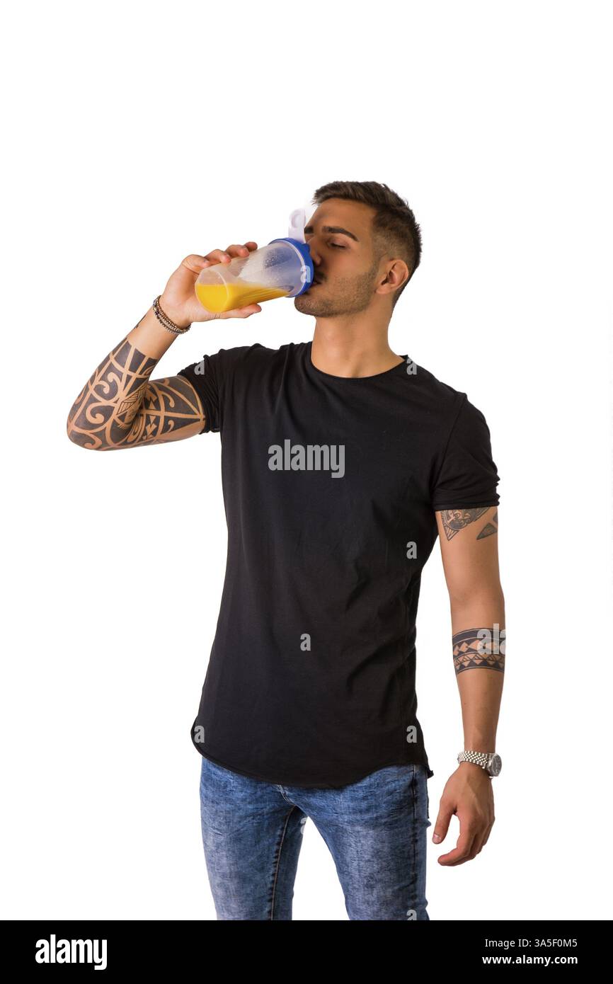 Attraktive tätowierte junge Mann halten und aus Protein Shaker Flasche trinken. Isoliert auf weiss Stockfoto