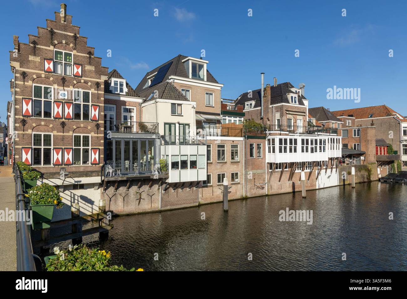 Typische Häuser mit rot-weißen Fensterläden in der befestigten Stadt Gorinchem entlang der Brücke und des Kanals Linge. Stockfoto