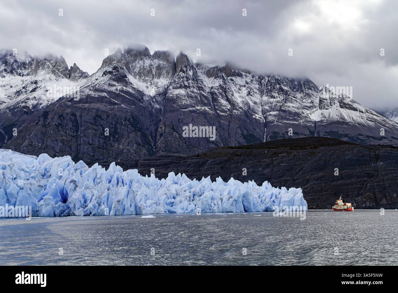 Der graue Gletscher ist ein blauer Gletscher in Patagonien, Chile. Großes Eis von Grau. Boot mit Touristen schwimmt zwischen Eisbergen. Der riesige Eisberg ist vom abgetrennt Stockfoto