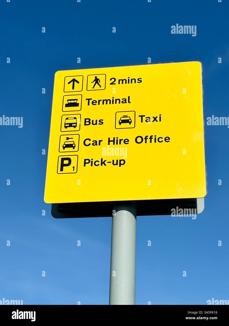 Flughafenschild: Schwarzer Text auf gelbem Hintergrund. Terminal, Bus, Taxi, Autovermietung, Abholung. Stockfoto