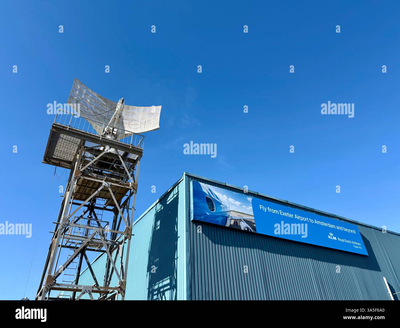 Exeter Airport, Exeter, Devon, März 2025: Radar und KLM-Schild „Fly from Exeter to Amsterdam and Beyond“ - Smartphone-aufgenommenes Stockfoto