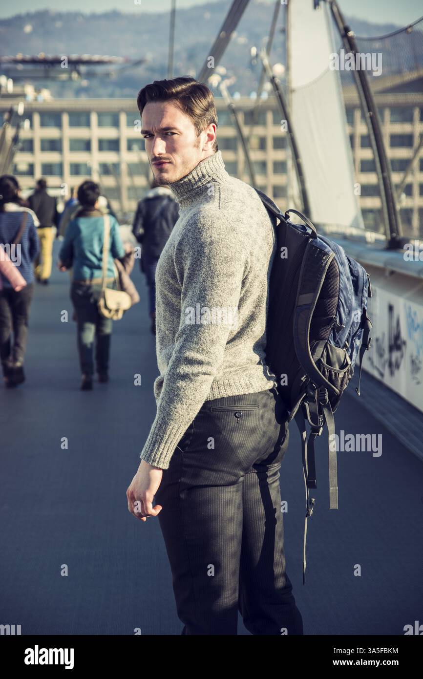 Hübscher junger Mann zu Fuß in die Stadt mit Rucksack auf der Schulter, tragen Winterkleidung Stockfoto