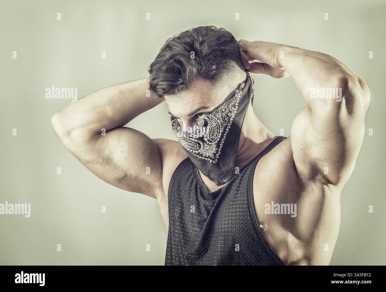 Schöner muskulöser junger Mann mit Maske über dem Gesicht als Räuber oder Räuber Stockfoto