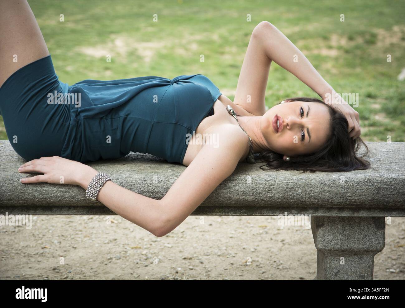 Attraktive elegante junge Frau Festlegung auf Steinbank, Blick in die Kamera Stockfoto