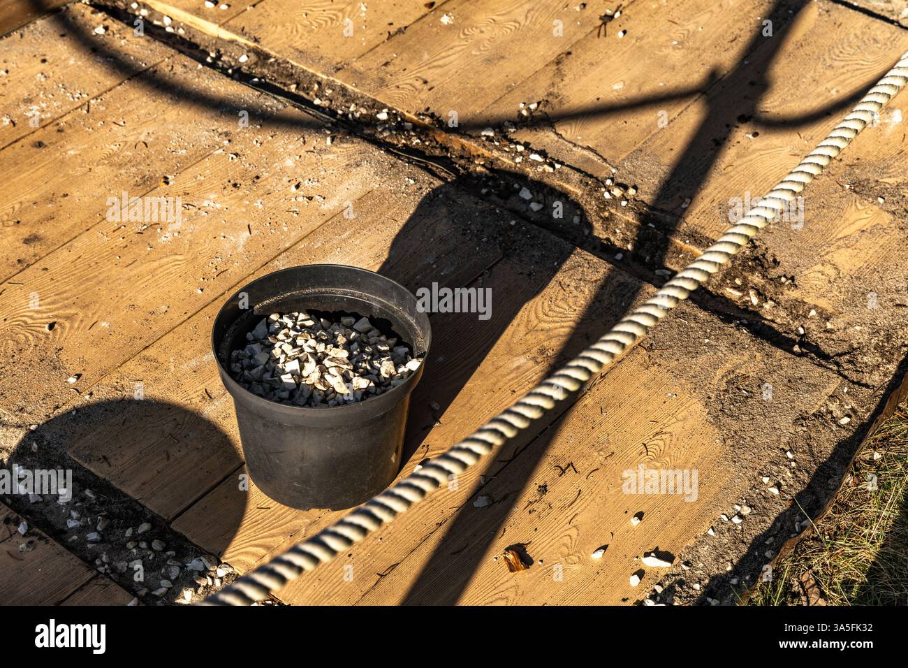 Dekorieren der Terrasse im Garten, Ausgießen kleiner weißer dekorativer Steine auf der Veranda im Garten, einen Eimer mit Steinen zur Dekoration Stockfoto