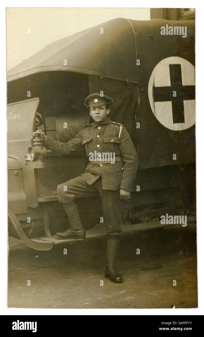Original-Postkarte aus der Zeit des 1. Weltkriegs mit einem jungen britischen Krankenwagenfahrer, Abzeichen des Army Service Corps (ASC) auf seiner Mütze, ein Schlüsselband auf der Schulter, neben dem Taxi seines Krankenwagens, rotes Kreuz auf der Seite. Der junge Mann hat vielleicht an einer der Motorenprüfschulen in London oder Glasgow ausgebildet. Soldaten des Ersten Weltkriegs. Britische Postkarte, 1914-1918. Stockfoto