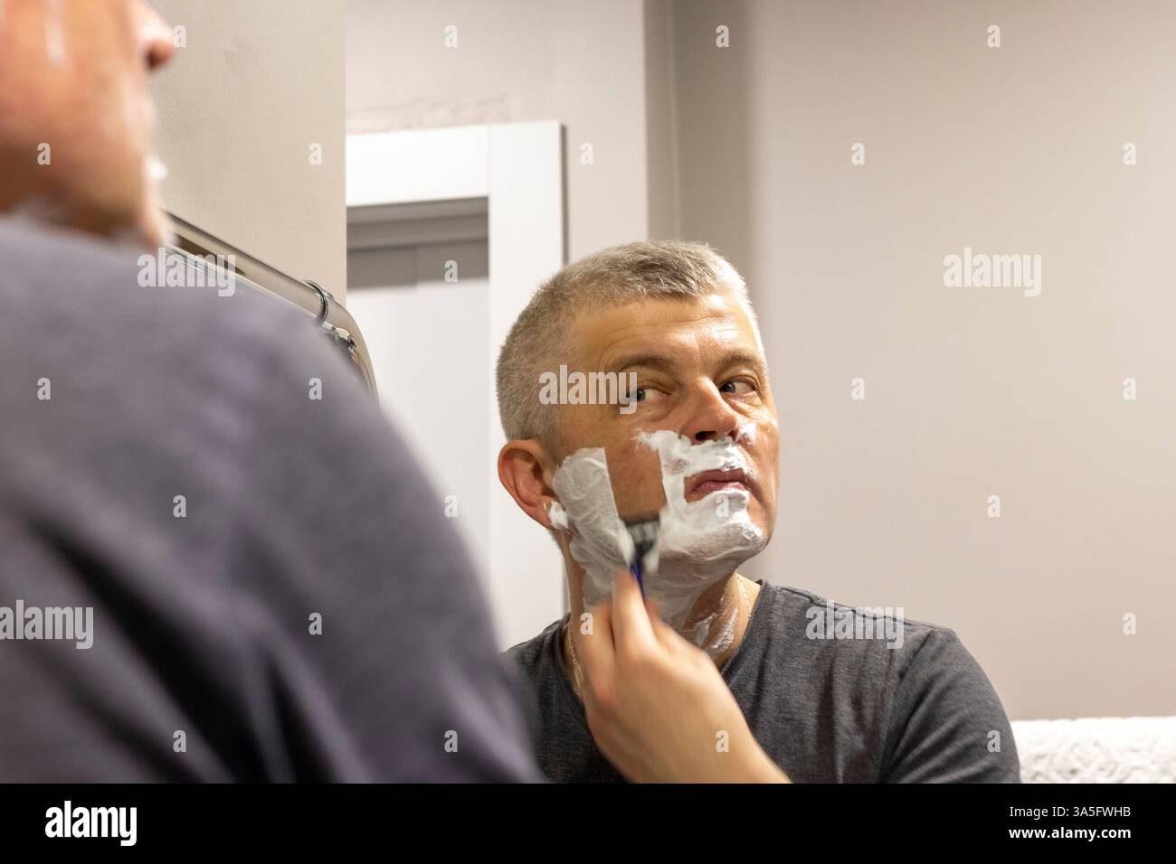 Reflexion im Spiegel des rasierenden Mannes Stockfoto