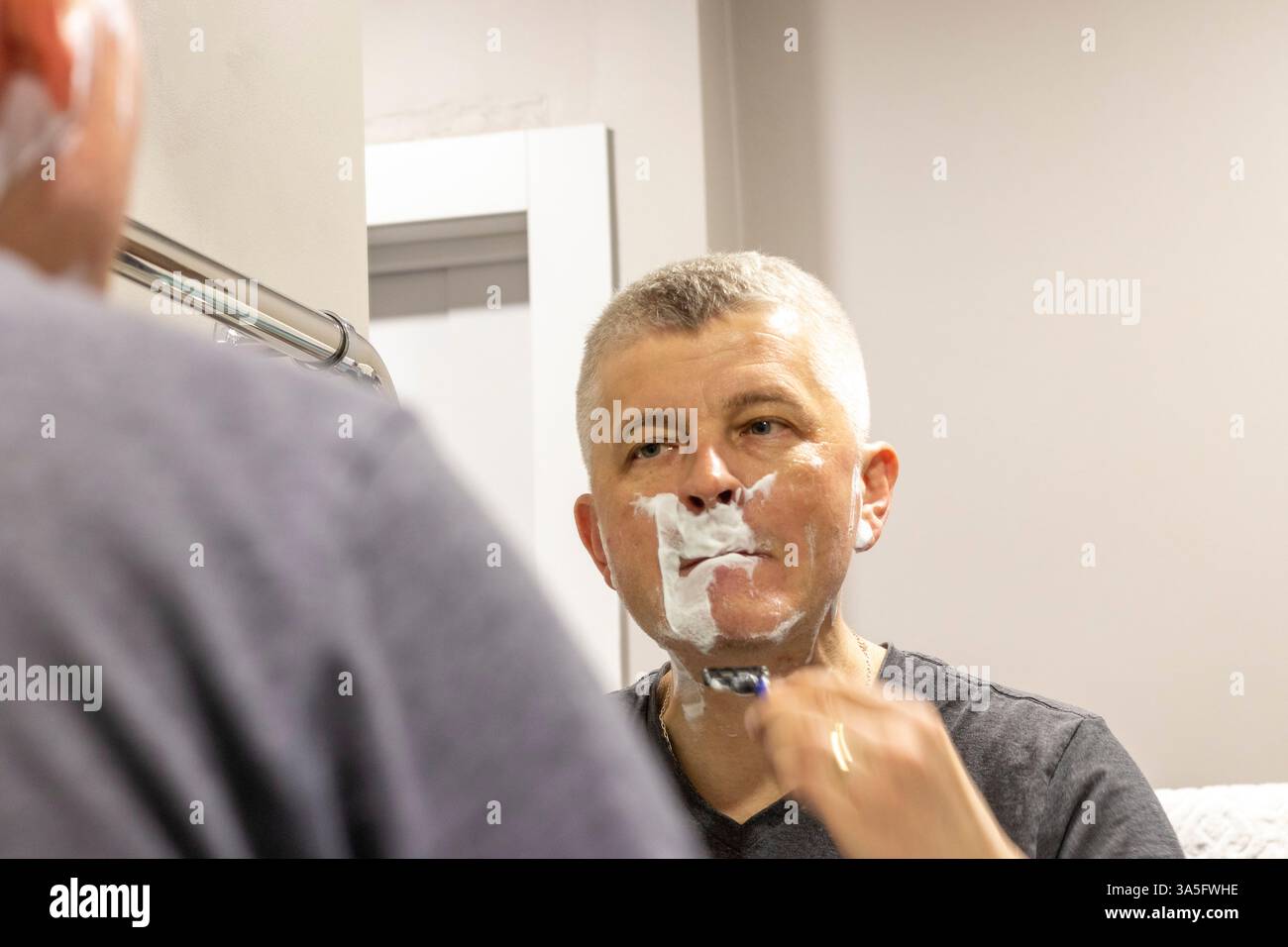 Reflexion im Spiegel des rasierenden Mannes Stockfoto