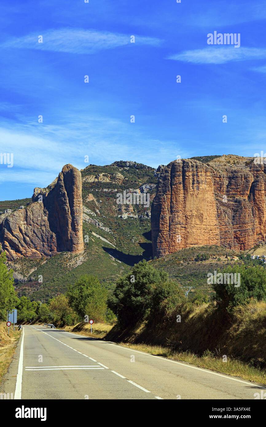 Asphalt Highway führt durch die Felsen. Teil der Ausläufer der Pyrenäen. Die Mallets von Riglos. Hoya de Huesca, Aragon. Heißer, sonniger Nachmittag. R Stockfoto