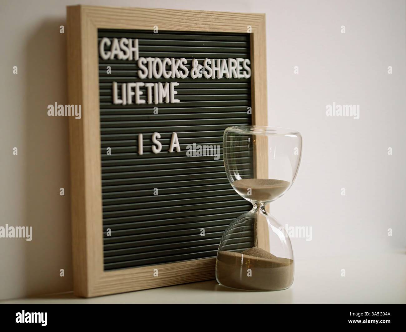 Ein hölzerner Rahmen mit Buchstaben Cash Stock und teilt lebenslange ISAs mit einer Stunde Glaszeit und Investition Stockfoto