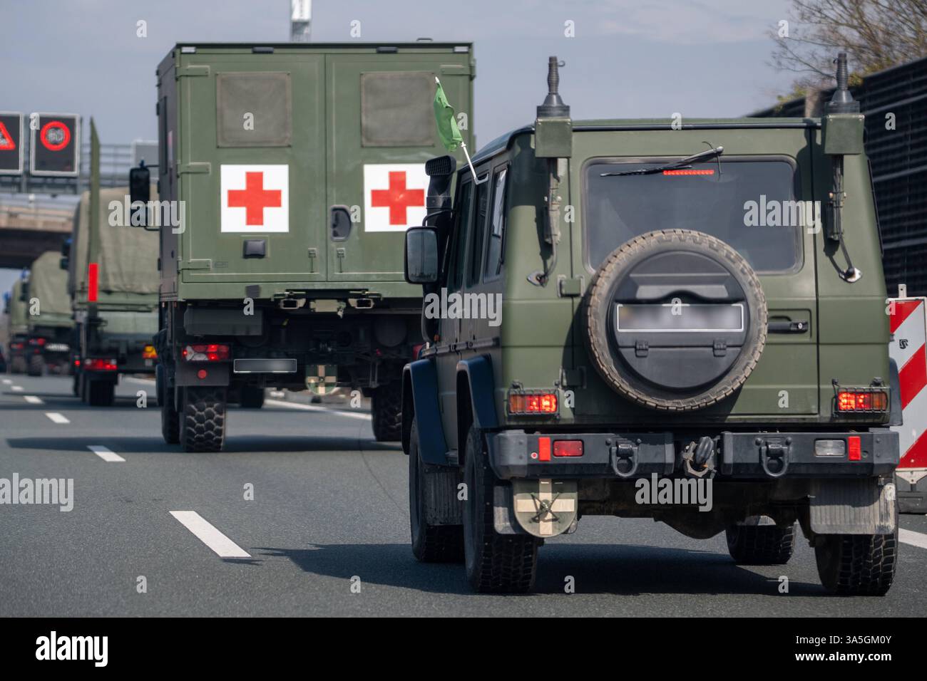 A9, Deutschland - 23. März 2025: Militärfahrzeuge mit Tarnlackierung und nicht erkennbaren litauischen Kennzeichen fahren auf der A9. Im Konvoi befindet sich ein medizinisches Fahrzeug mit zwei roten Kreuzen und einer grünen Flagge. *** Militärfahrzeuge mit Tarnlackierung und litauischem Kennzeichen unenntlich fahren auf der A9. Im Konvoi befindet sich ein Sanitätsfahrzeug mit zwei roten Kreuzen und grüner Fahne. Stockfoto