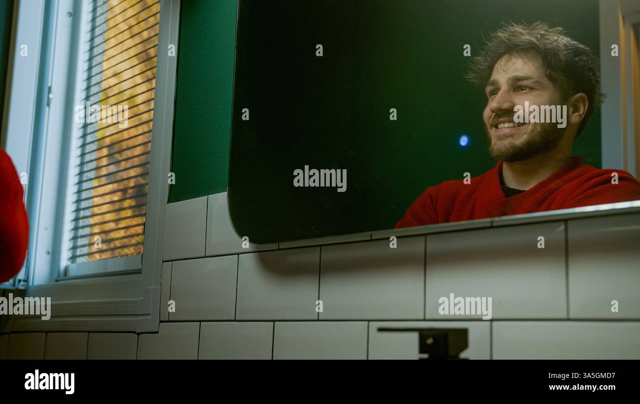 Mann lächelt sich im Spiegel an – Selbstvertrauen, Glück und Selbstfürsorge-Badszene Stockfoto