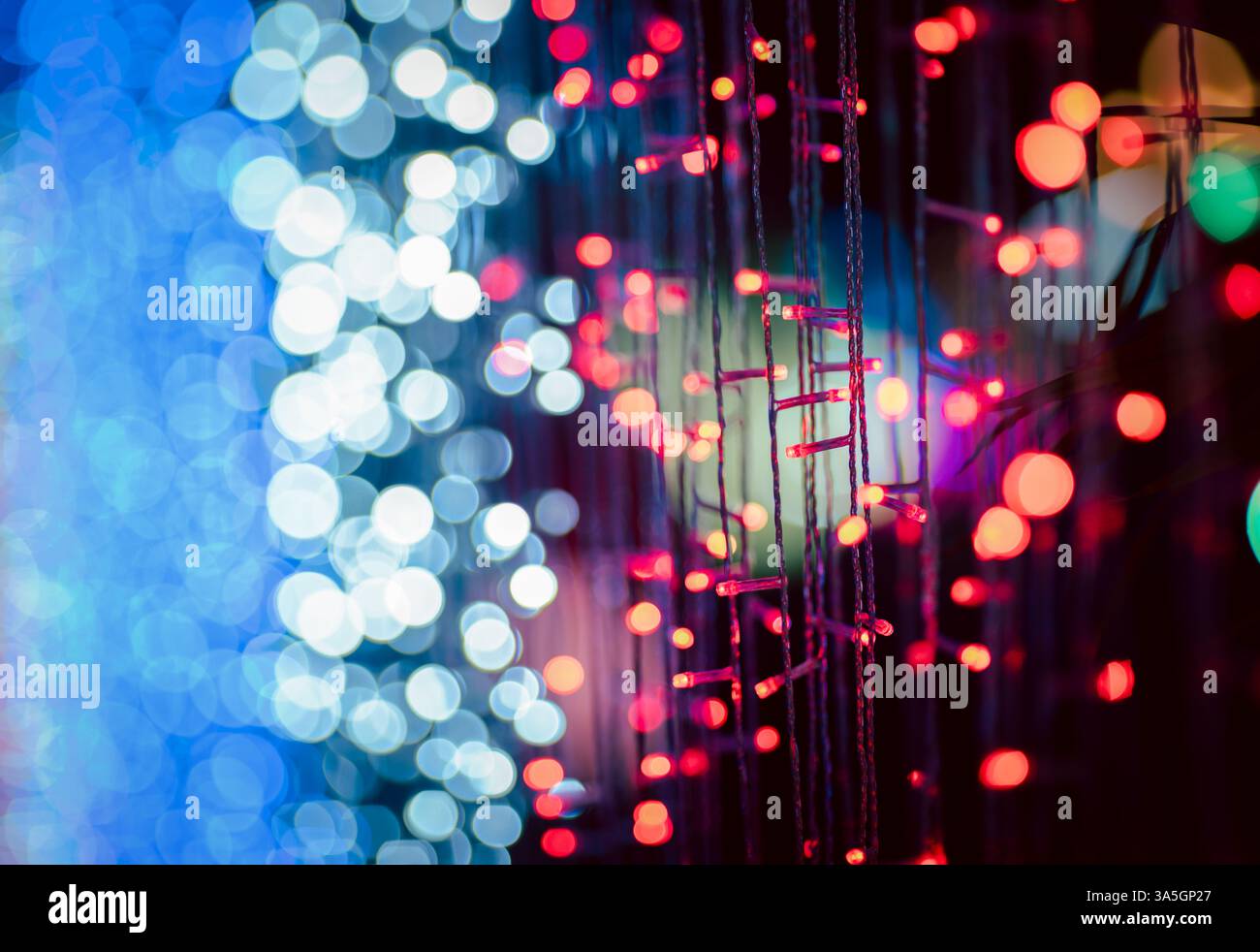 Abstrakte bunte Bokeh-Kugeln auf dunklem Hintergrund, lebendiges, defokussiertes Lichtpunktmuster, festliche Overlay-Textur für Fotobearbeitung, unscharfer, heller Zirkus Stockfoto