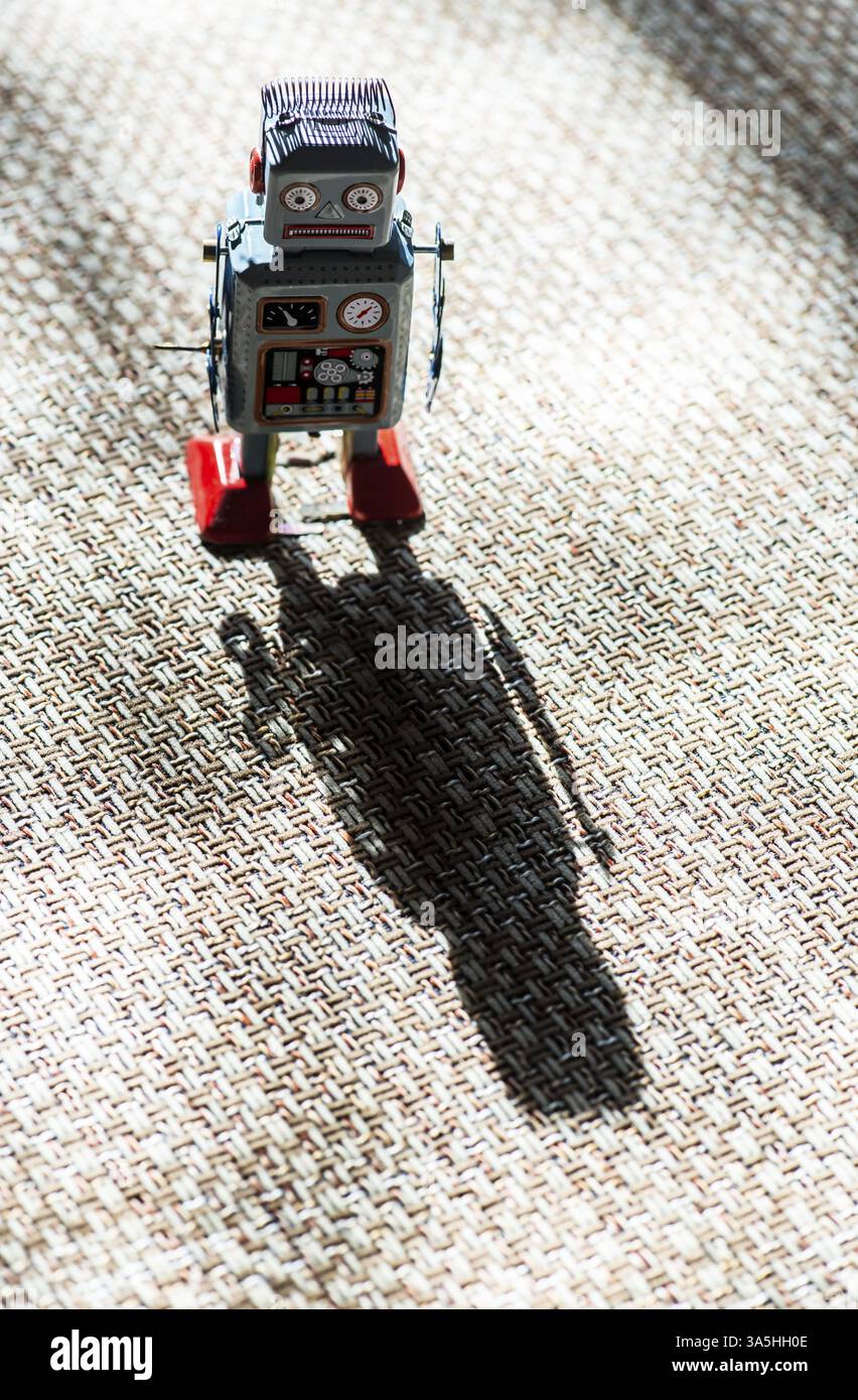 Vintage Metall blau Roboter Spielzeug auf Sonneneinstrahlung. Futuristisches Konzept mit kleinen mechanischen Roboter Spielzeug zu Fuß auf Tuch Oberfläche. Gemalte Augen und elektronischen das Stockfoto