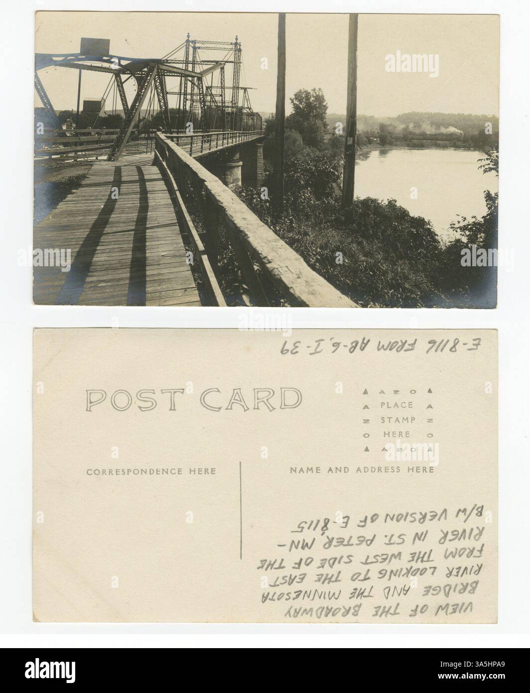Diese Postkarte zeigt einen Blick auf die Broadway Bridge über den Minnesota River in St. Peter. Ein Getreideaufzug, das Bahnbetriebswerk und ein Zug, der von einer Dampflokomotive gezogen wird, sind in der Ferne sichtbar. Stockfoto