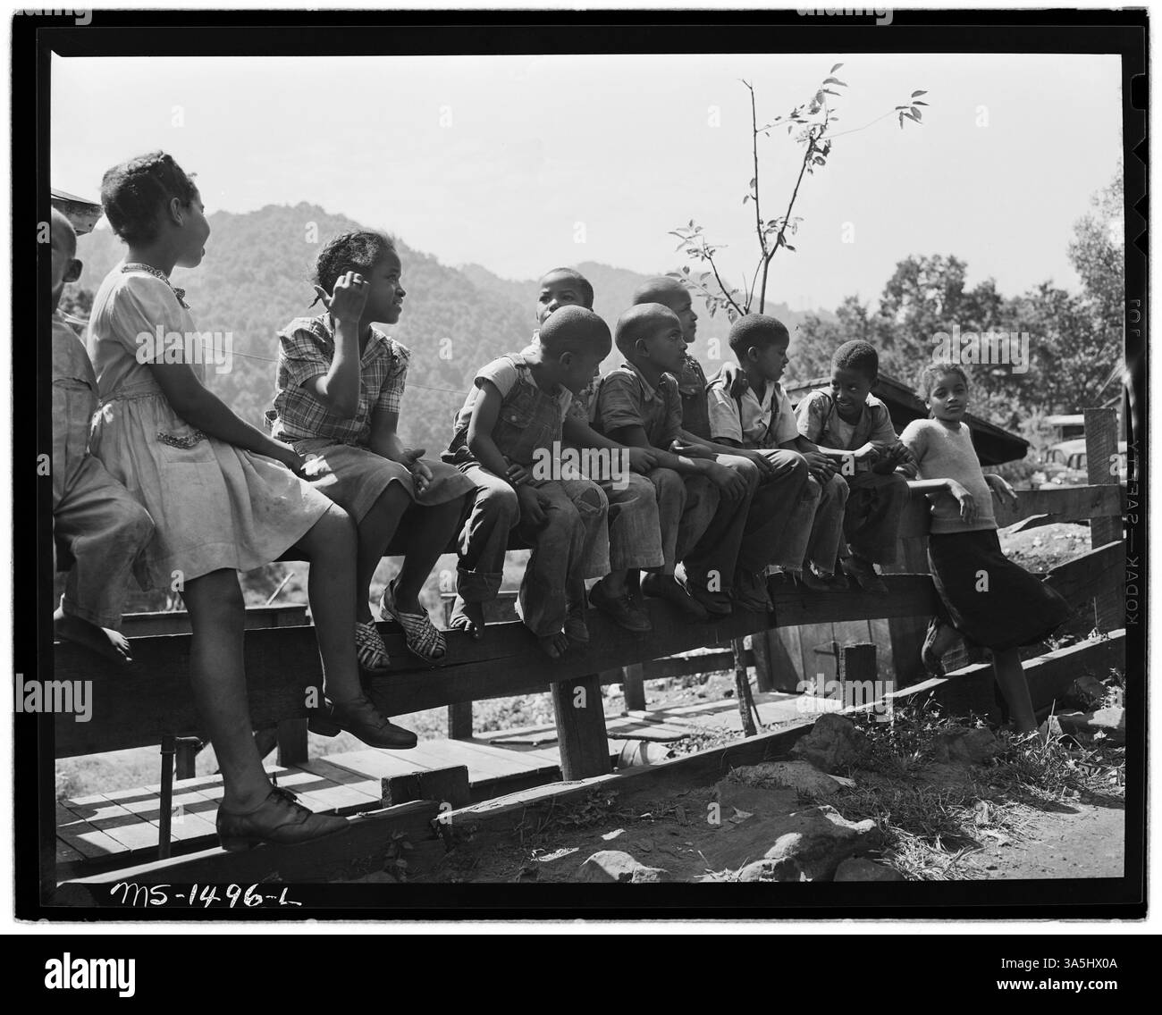 Kinder von Bergleuten spielen auf einem Zaun vor dem Howard House in Gilliam, McDowell County, West Virginia. Das Bild ist im Nationalarchiv archiviert. Stockfoto