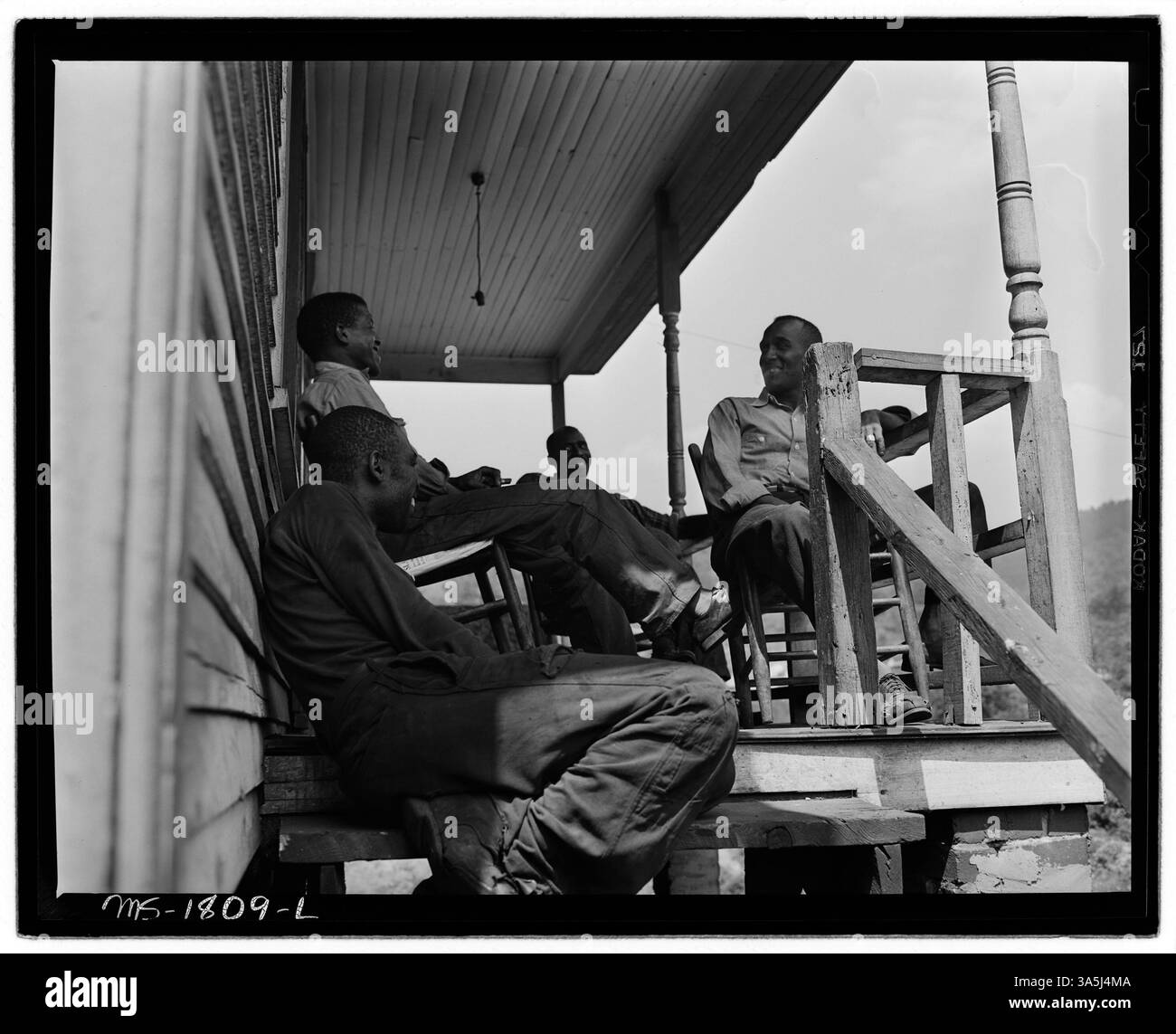 Eine Gruppe von vier Steinkohlebergleuten steht auf den vorderen Stufen ihres Hauses in der Nähe der Mullens Smokeless Coal Company in Mullens, West Virginia, wo sie sich ihren Wohnraum teilen und ihre eigene Küche verwalten. Stockfoto