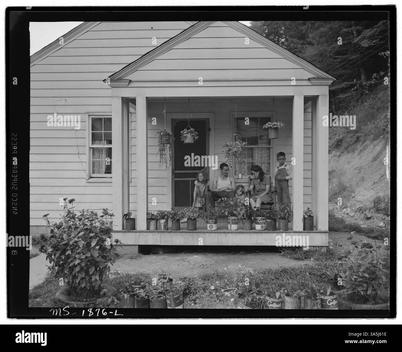 T. J. Martin, ein Bergarbeiter, wird mit seiner Familie auf der Veranda ihres Hauses abgebildet. Er zog vor 13 Monaten in die Gegend, um in den Minen der Koppers Coal Division zu arbeiten, und hat jetzt genug gespart, um wieder in die Landwirtschaft im Floyd County, Kentucky, zurückzukehren. Das Foto stammt von Kopperston Mines im Wyoming County, West Virginia. Stockfoto