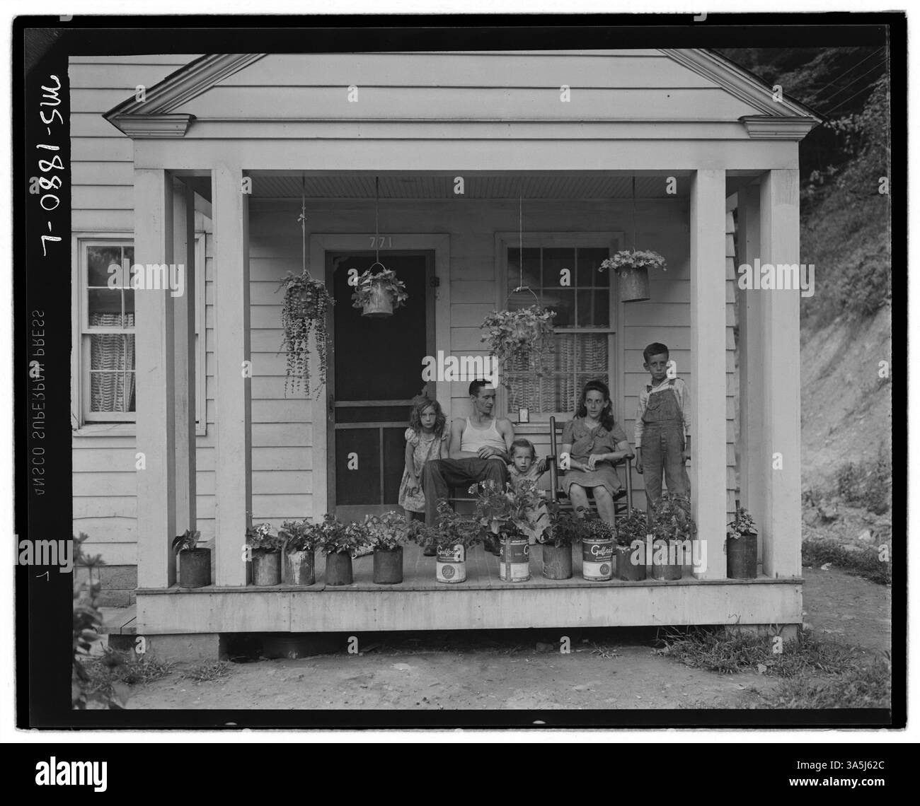 T. J. Martin, ein Bergarbeiter, ist mit seiner Familie auf der Veranda ihres Hauses in Kopperston, Wyoming County, West Virginia, abgebildet. Nachdem er 13 Monate in der Koppers Coal Division gearbeitet hatte, sparte Martin genug, um auf seine Farm im Floyd County, Kentucky, zurückzukehren. Stockfoto