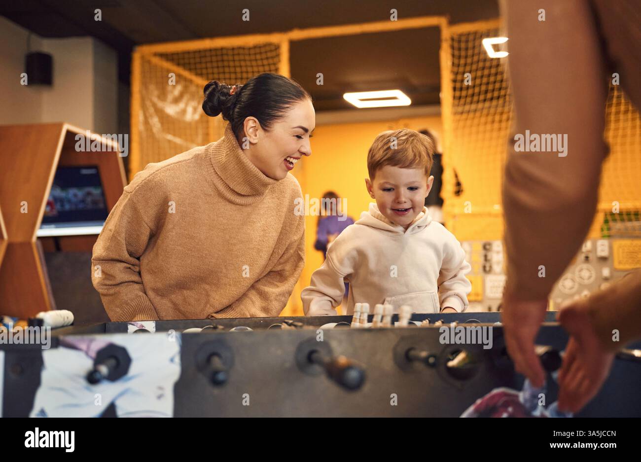 Spaß haben. Familie von Vater, Mutter und Sohn, die Tischfußballspiel drinnen spielen. Stockfoto