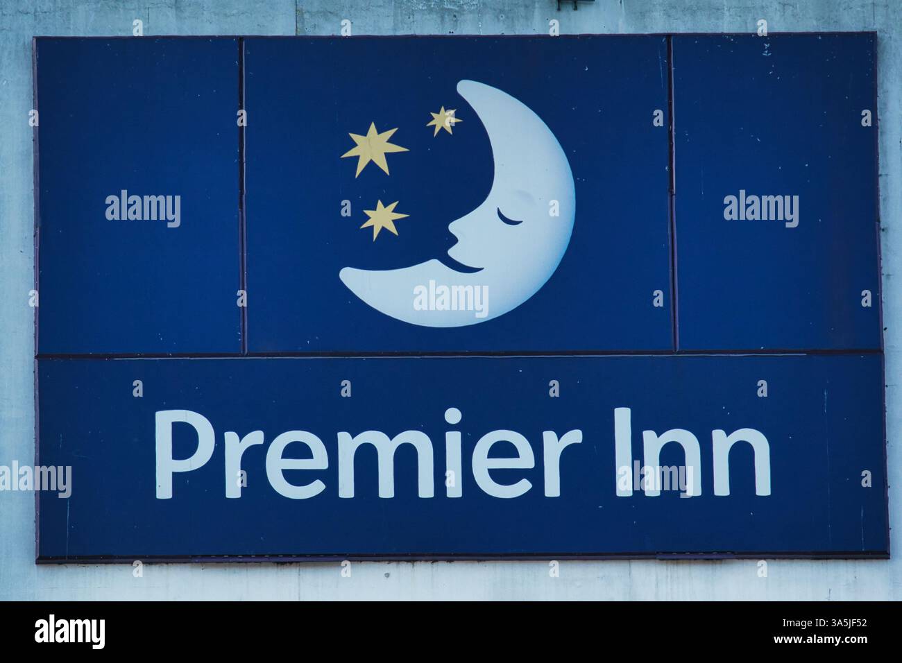 Hotelschild mit „Premier Inn“-Text und einem Mond- und Sternelogo an einer Wand. Die vorherrschenden Farben sind Blau und weiß in Manchester, Großbritannien. Stockfoto