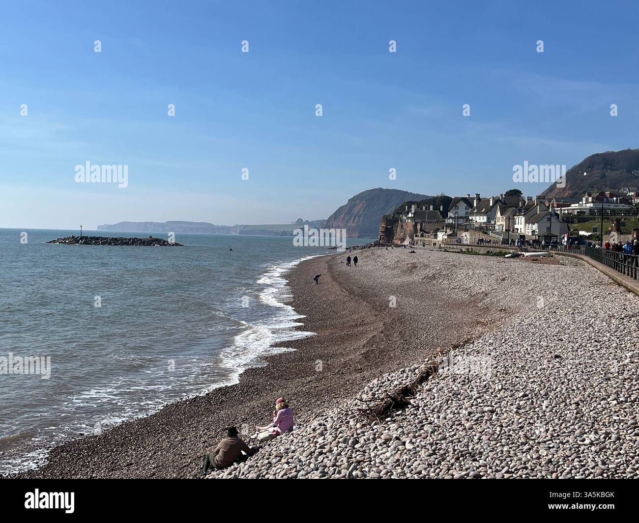 Die Leute saßen am Strand von Sidmouth in Devon Stockfoto