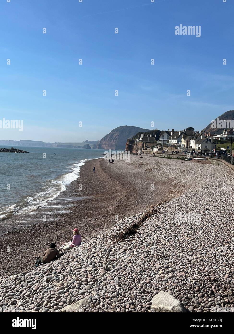 Die Leute saßen am Strand von Sidmouthin Devon Stockfoto