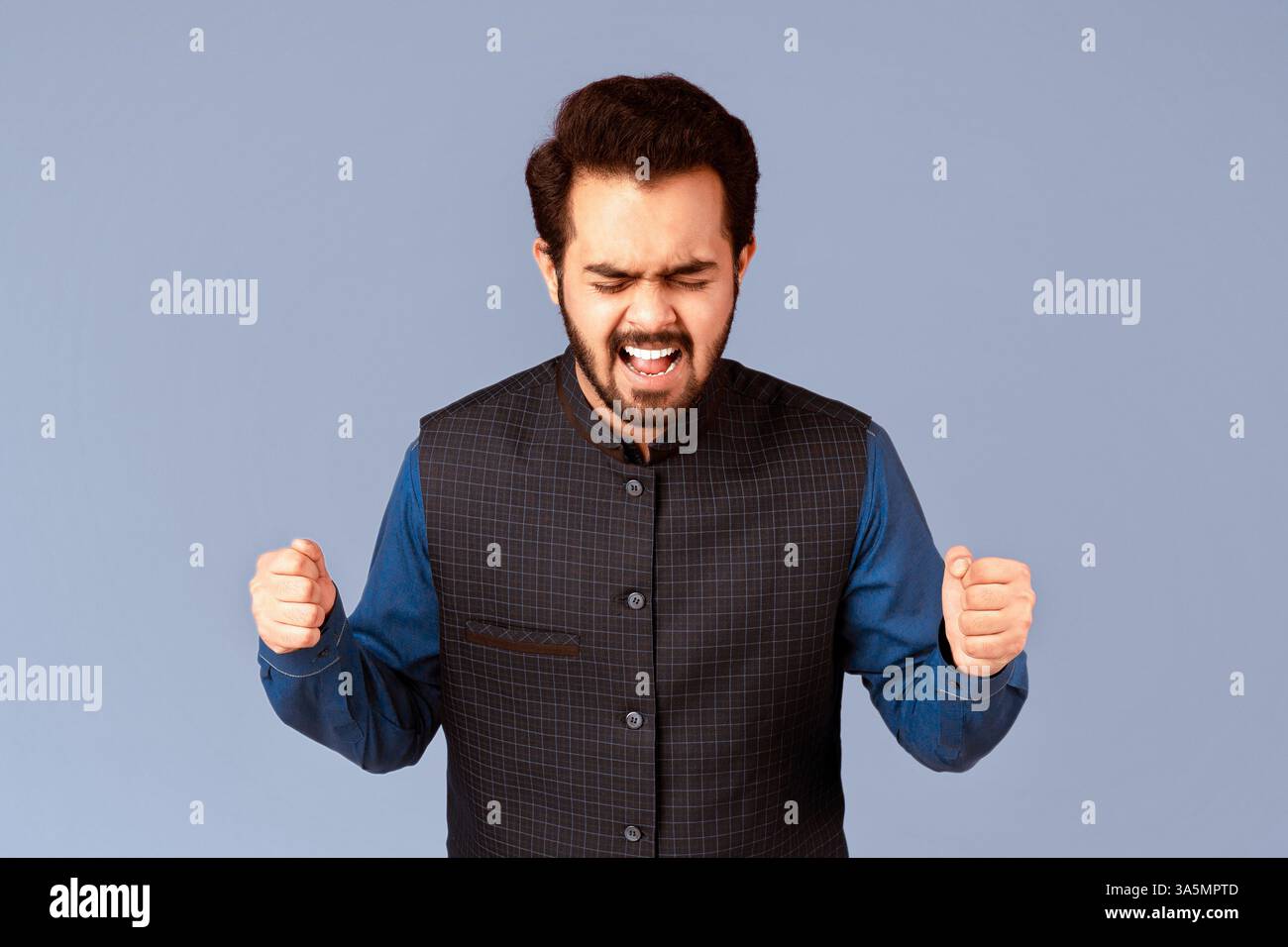 Wütender indischer Mann, der sich vor Wut die Fäuste zusammenhält und anschreit Lila Hintergrund Stockfoto