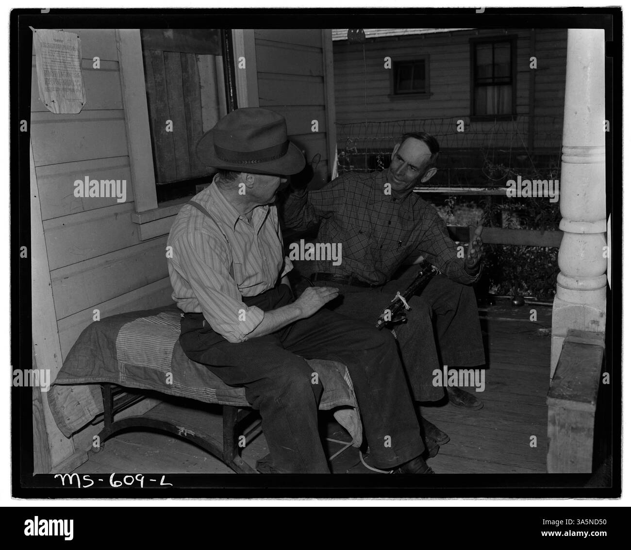 Irving Bittick, ein Bergarbeiter, wird auf der Veranda seines Hauses in der Kenilworth Mine im Carbon County, Utah, gesehen und plaudert mit einem Freund über seine Angelerfahrung. Stockfoto