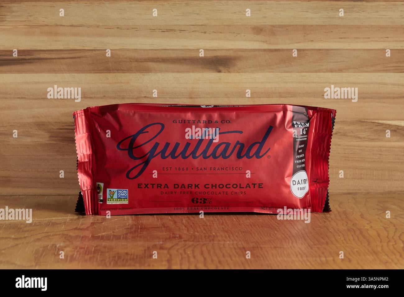 Tasche mit extra dunklen milchfreien Schokoladenchips der Marke Guittard, einer amerikanischen Schokoladenfirma, auf rustikalem Holzhintergrund mit Kopierraum Stockfoto