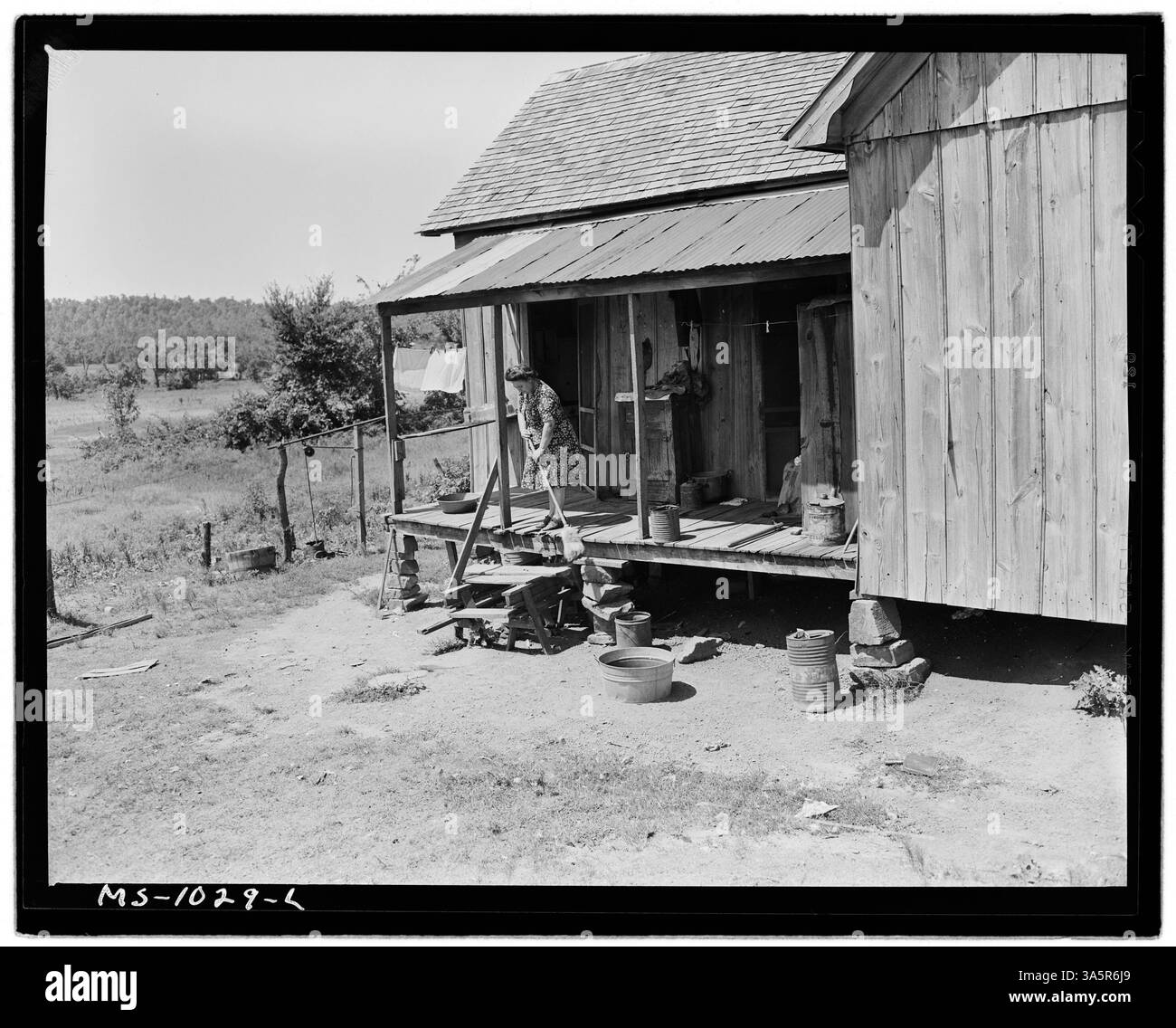 Mrs. Luther Nixon, die Frau eines Bergarbeiters, wird gezeigt, wie sie die hintere Veranda ihres Bauernhauses in Le Flore County, Oklahoma, fegt. Ihr Mann ist bei der Paul Reese Coal Company beschäftigt. Nationalarchiv im College Park. Stockfoto