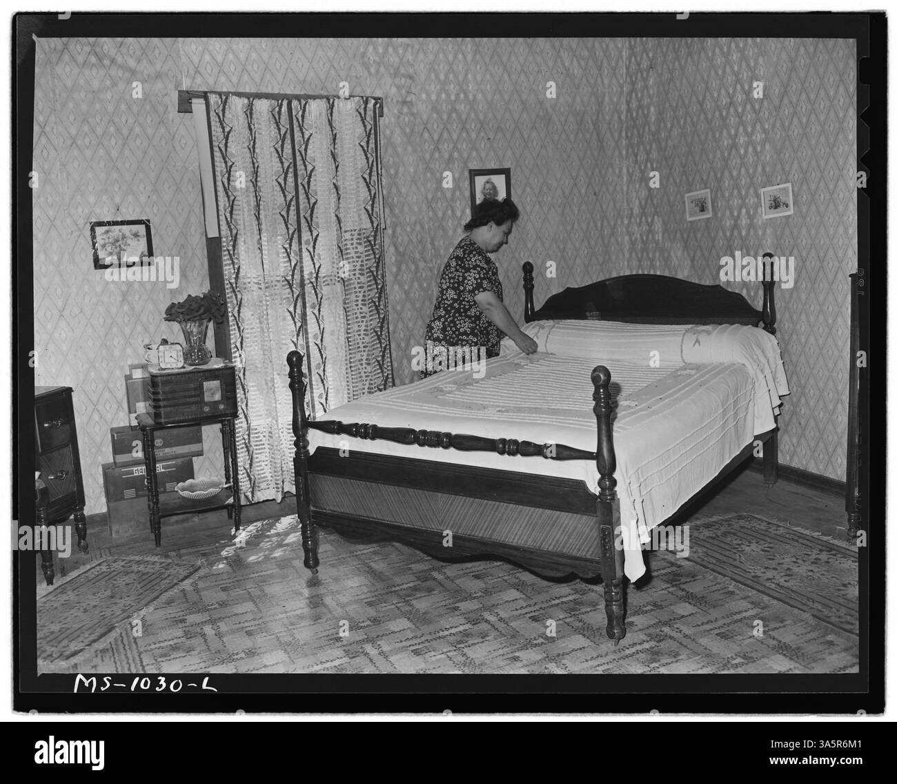 Mrs. Luther Nixon macht das Bett in ihrem Farmhaus in Le Flore County, Oklahoma, wo ihr Mann, Mr. Nixon, bei der Paul Reese Coal Company arbeitet. Stockfoto