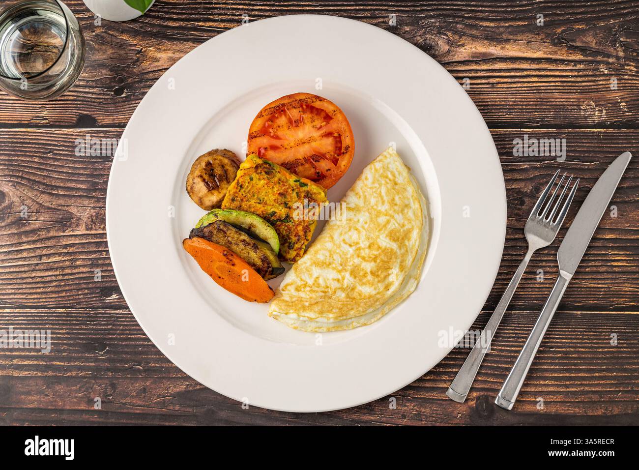 Rustikaler Frühstücksteller mit Spiegeleiern, gegrilltem Gemüse und putenspeck Stockfoto