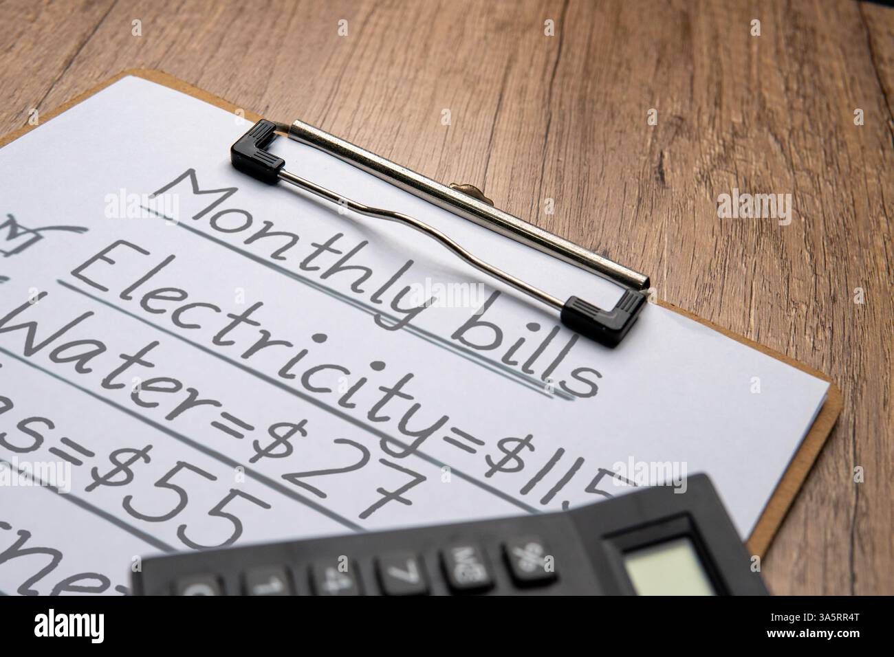 Taschenrechner und eine Zwischenablage aus Papier mit einer handgeschriebenen Monatsliste. Haushaltsbudgetplanung und persönliches Finanzmanagement. Stockfoto