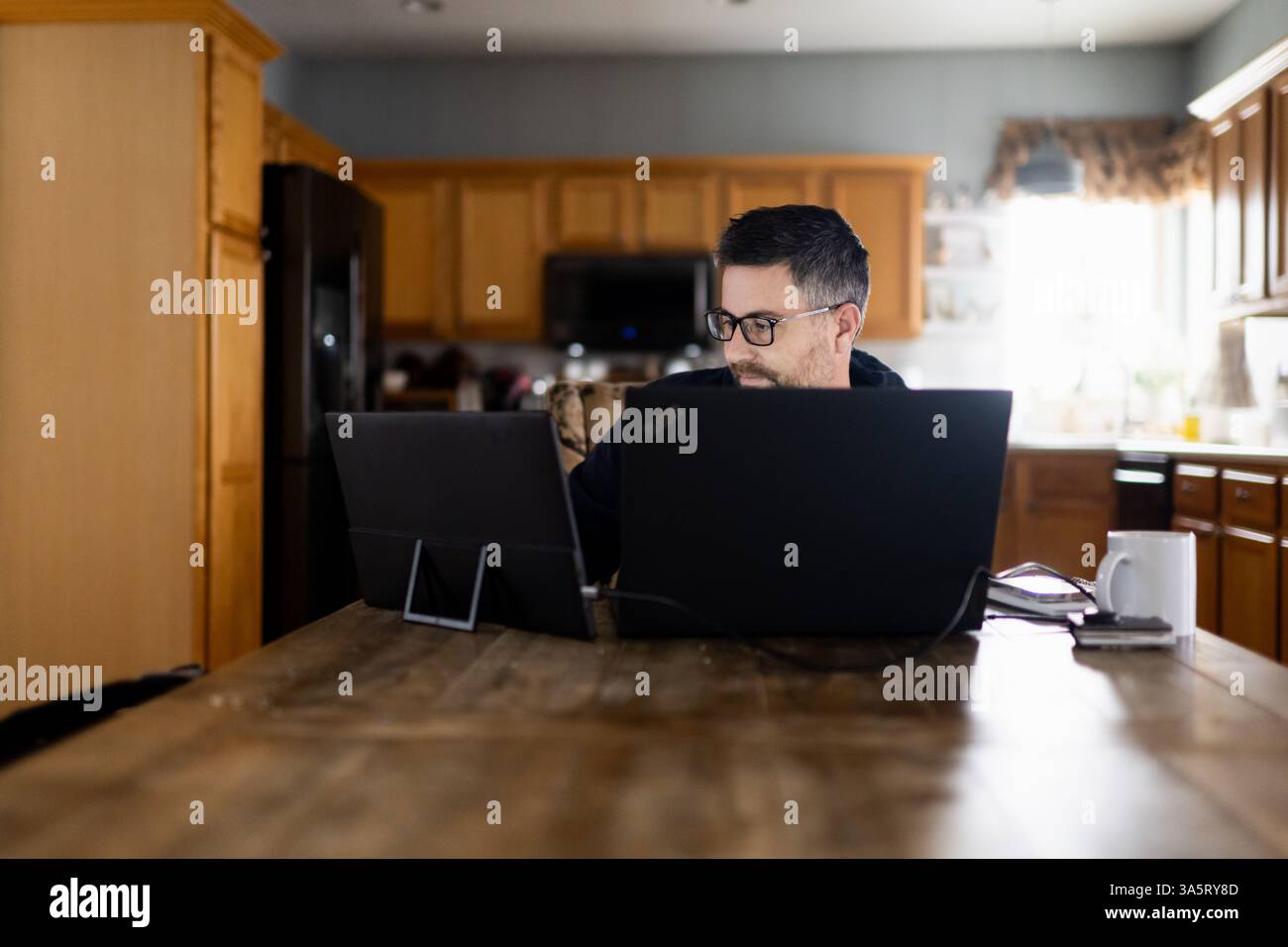 Erwachsener Mann in Brille, der morgens von zu Hause aus arbeitet Stockfoto