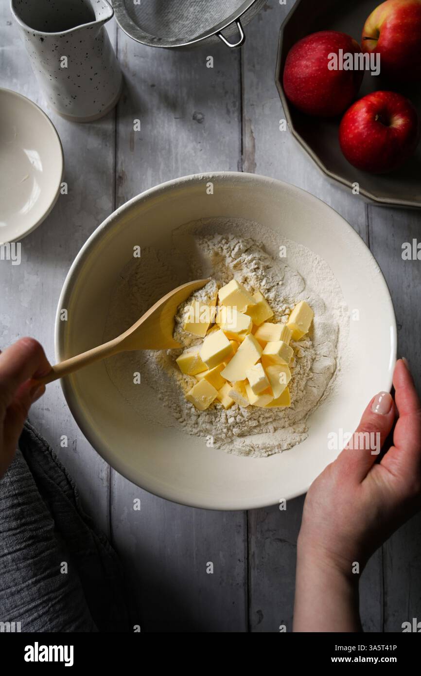 Hausbackkonzept. Eine Schüssel mit weißem Mehl, Äpfeln und Butter Stockfoto