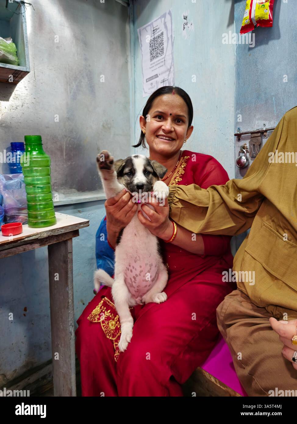 Eine nepalesische Frau, die ihren Welpen hält. Foto in Kathmandu, Nepal. - Smartphone-aufgenommenes Stockfoto