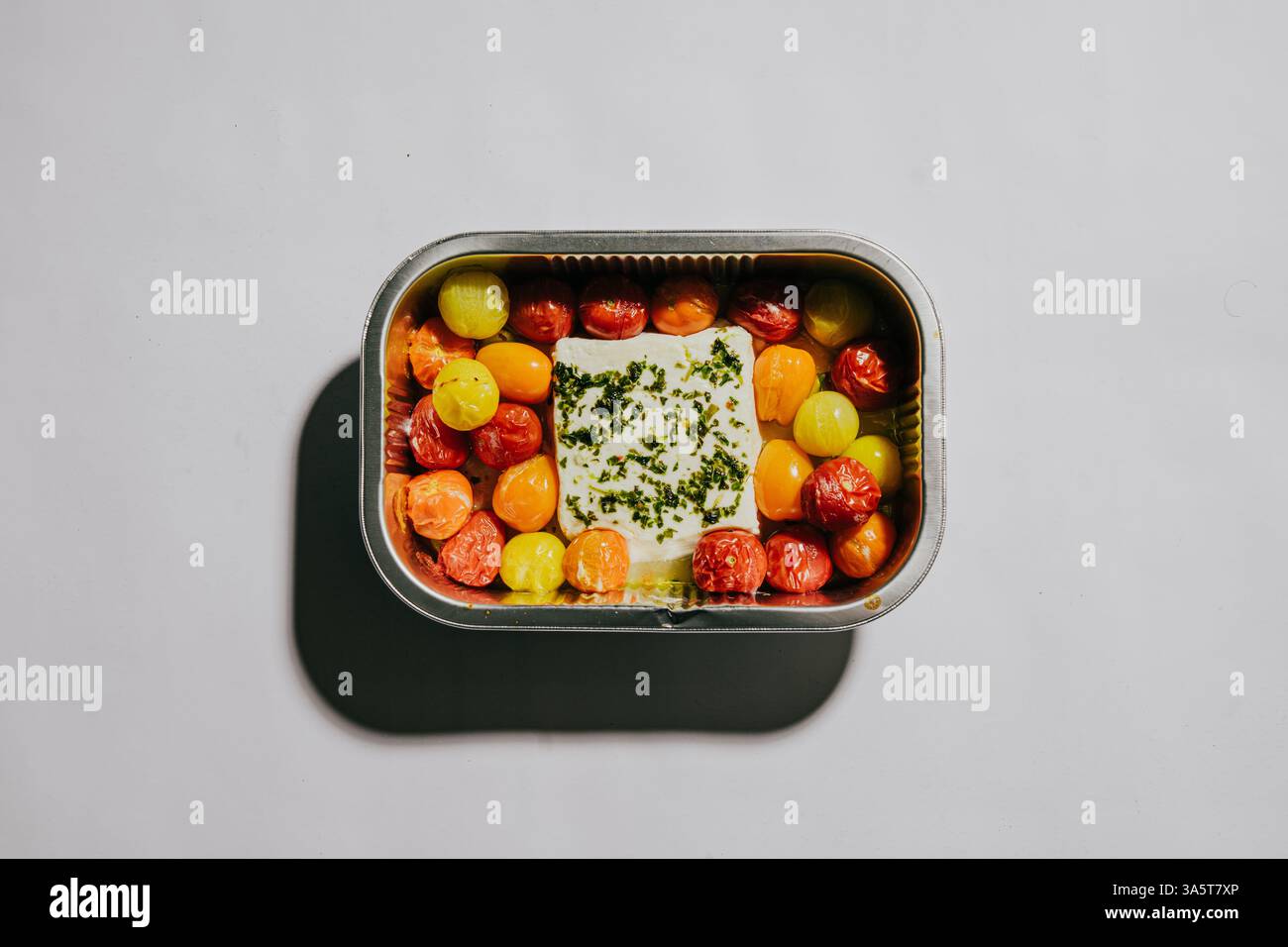 Ein kleiner Behälter mit Lebensmitteln mit einer Vielzahl von Obst und Gemüse. Der Behälter ist silber und hat einen Deckel Stockfoto