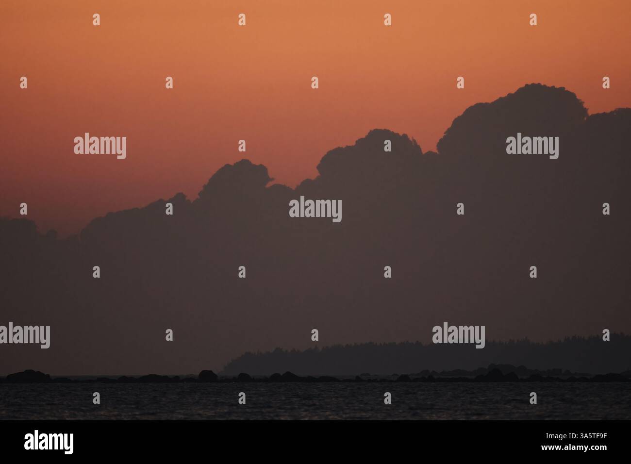 Sonnenuntergang am Meer mit dunklen Wolken, die am Horizont aufsteigen. Stockfoto