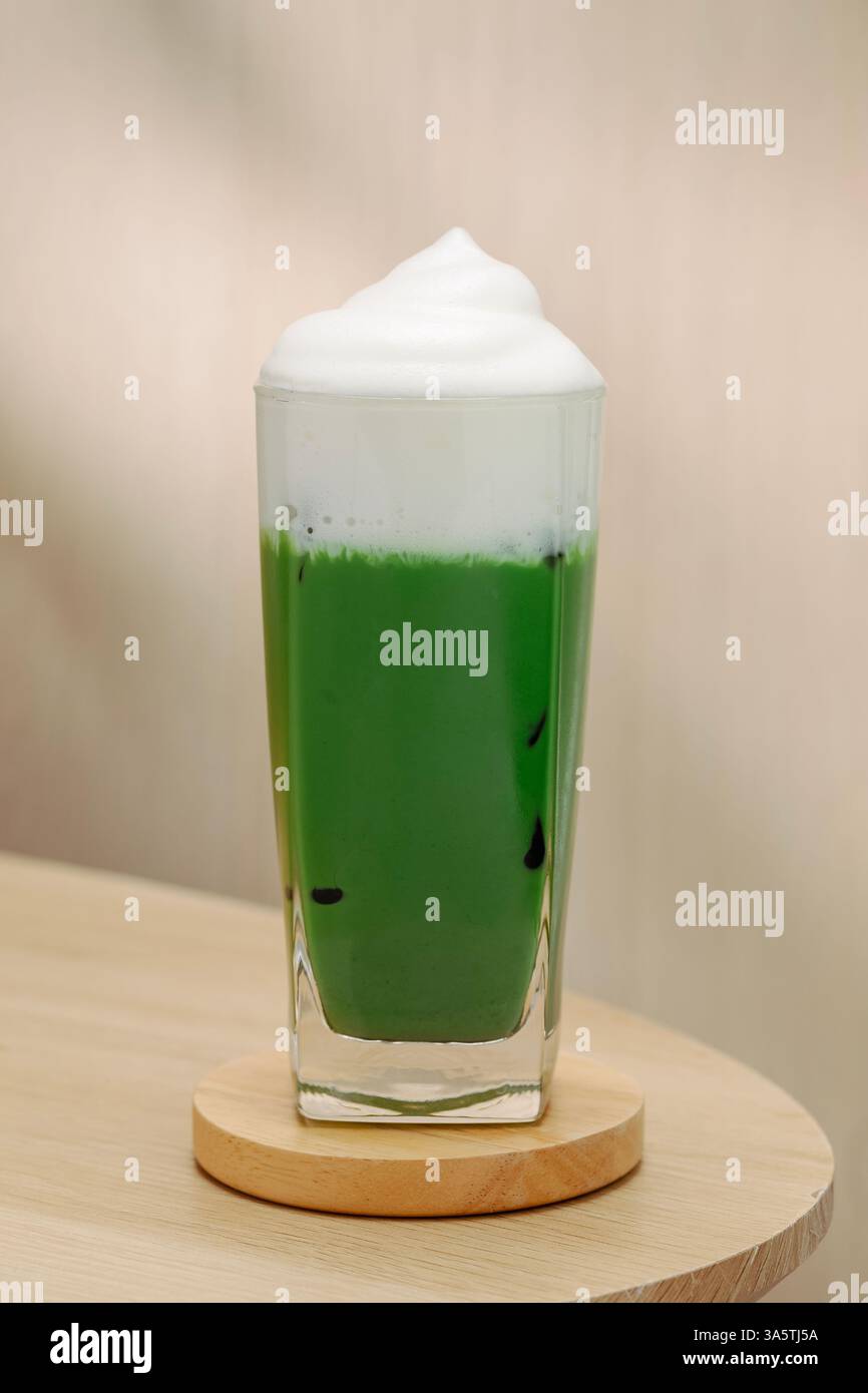 Eismatcha mit Milchschaum auf einem Holztisch. Eine perfekte Mischung aus Aromen und Texturen. Stockfoto