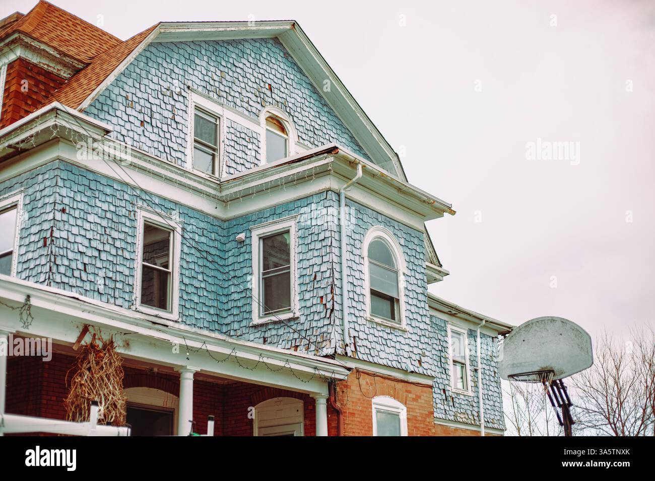 Der obere Teil der Fassade eines dreistöckigen Hauses mit blauen und Ziegelsteinen aus einem niedrigen Winkel in Philadelphia, Pennsylvania, USA, 23. März 2025. Stockfoto
