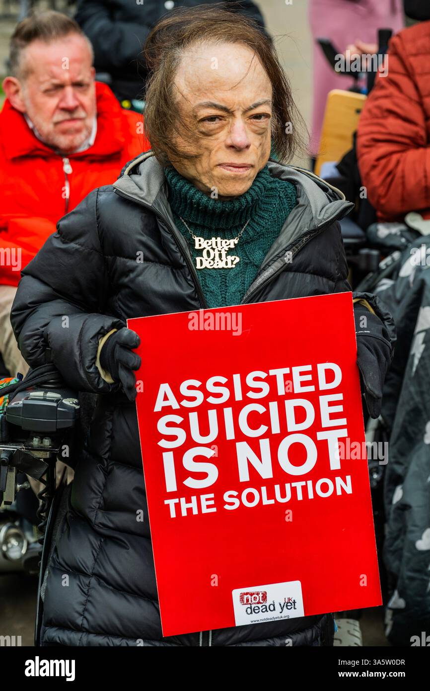 London, Großbritannien. März 2025. Liz Carr schließt sich dem Protest mit einer Kette an, die sagt: "Lieber tot?" - Behinderte Gegner (mit Plakaten, auf denen steht, dass Assisted Suicide nicht die Antwort ist und sie "noch nicht tot" sind) des britischen Sterbegesetzes kommen nach Westminster und treffen sich auf College Green vor dem parlament, um zu protestieren, während das Gesetz seine Ausschussphase durchläuft. Guy Bell/Alamy Live News Stockfoto