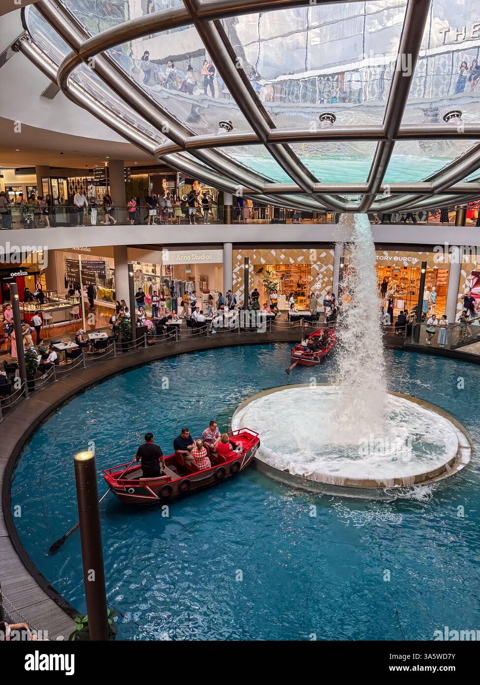 Das Einkaufszentrum Marina Bay Sands mit einem Kanal, der durch ihn führt, und Menschen auf Booten. Stockfoto