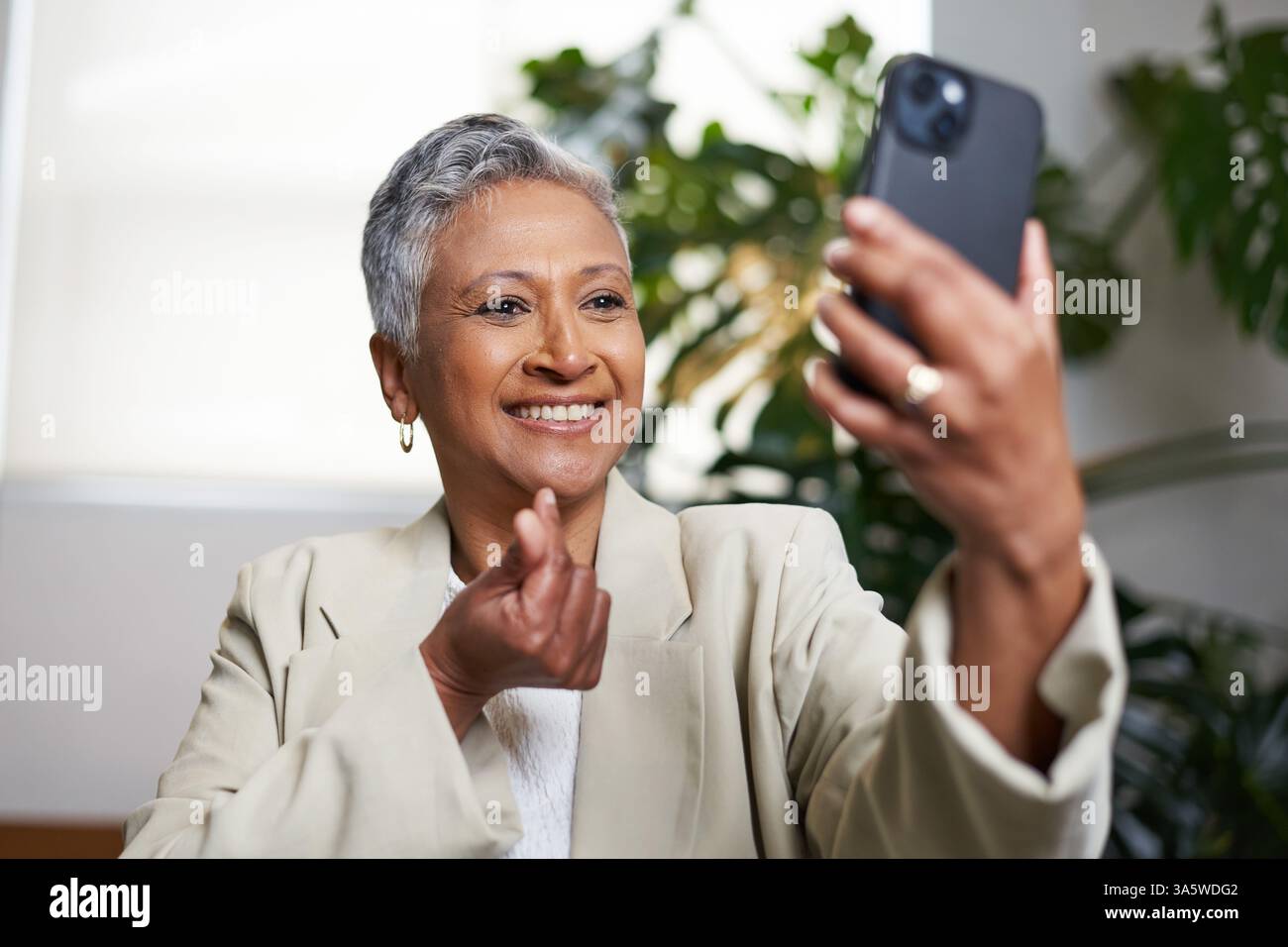 Eine ältere Frau führte einen Videoanruf mit ihrem Smartphone in einer komfortablen Innenumgebung durch Stockfoto