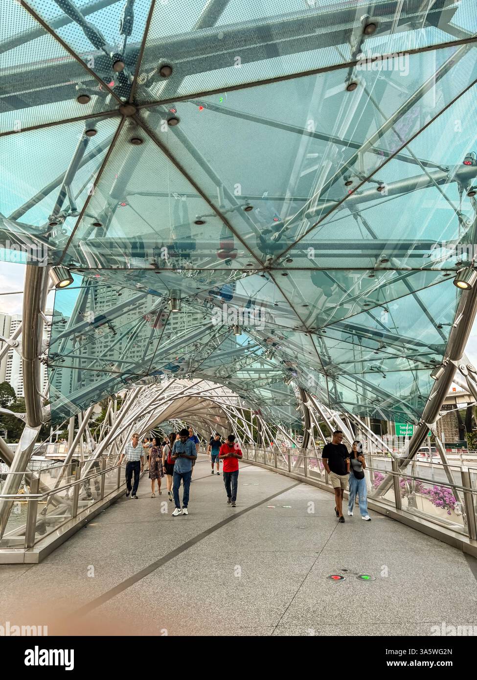 Die Helix Bridge in Singapur hat eine einzigartige Doppelspirale. Fußgänger gehen über die berühmte Brücke mit Blick auf die Skyline der Stadt. Stockfoto