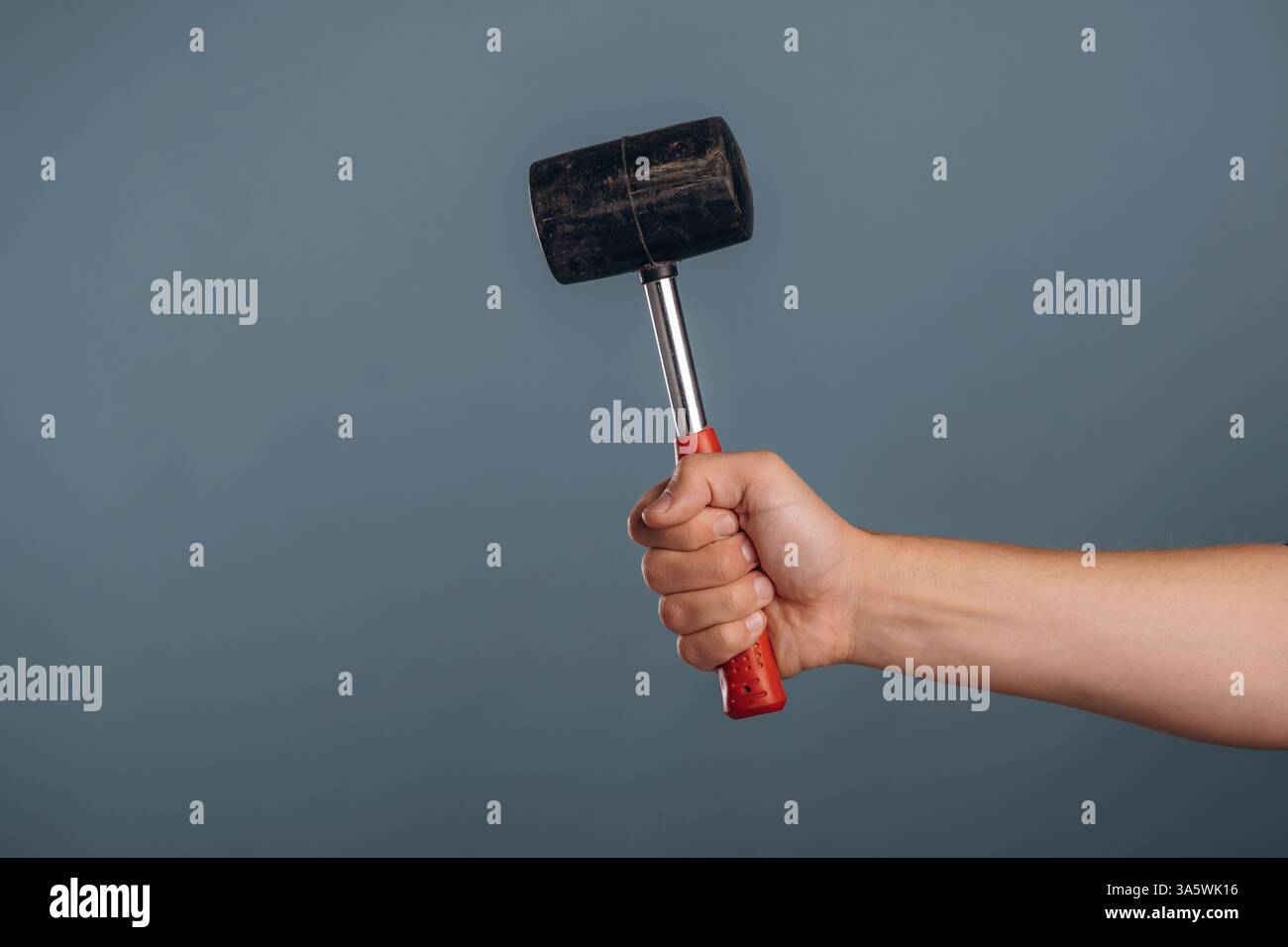 Die Hand des Mannes hält einen professionellen Hammer vor dem Hintergrund. Stockfoto